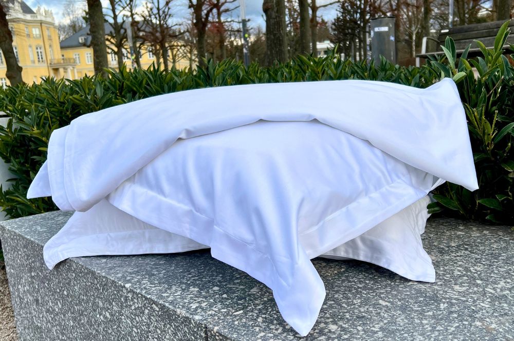 Ein Stapel weicher weißer Kissen auf einer Granitbank im Freien in einer ruhigen und eleganten Atmosphäre