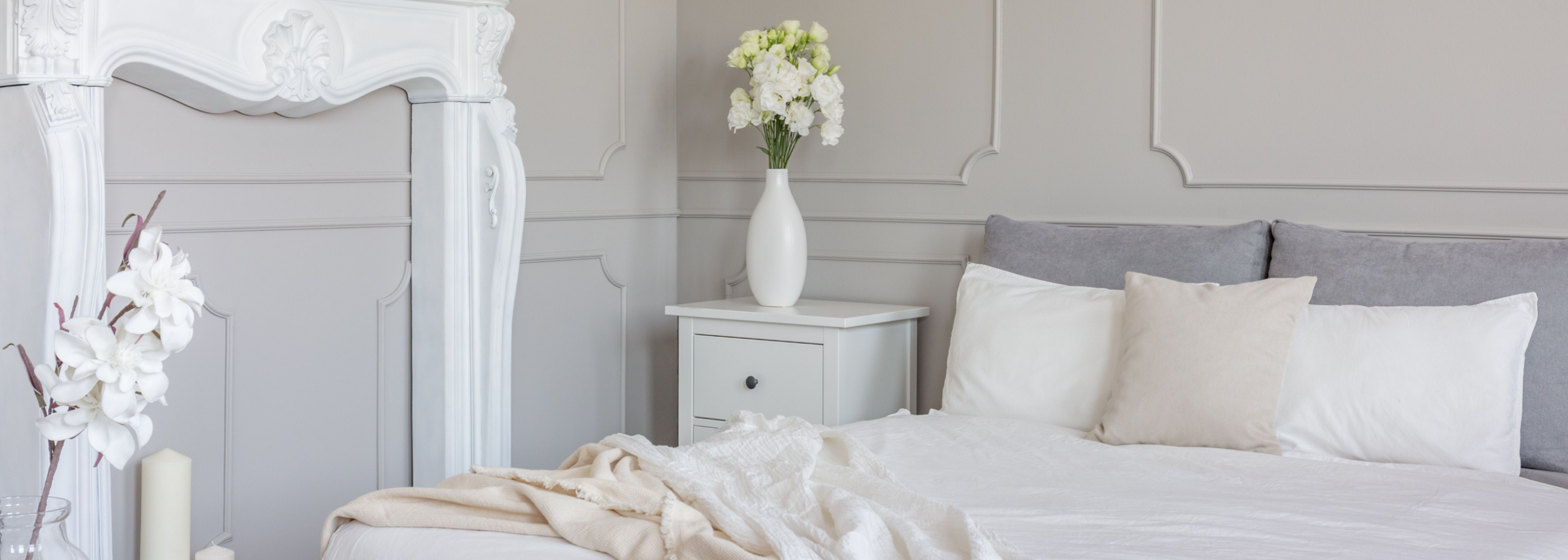 Ein Schlafzimmer mit einem weißen Bett und einer weißen Kommode.