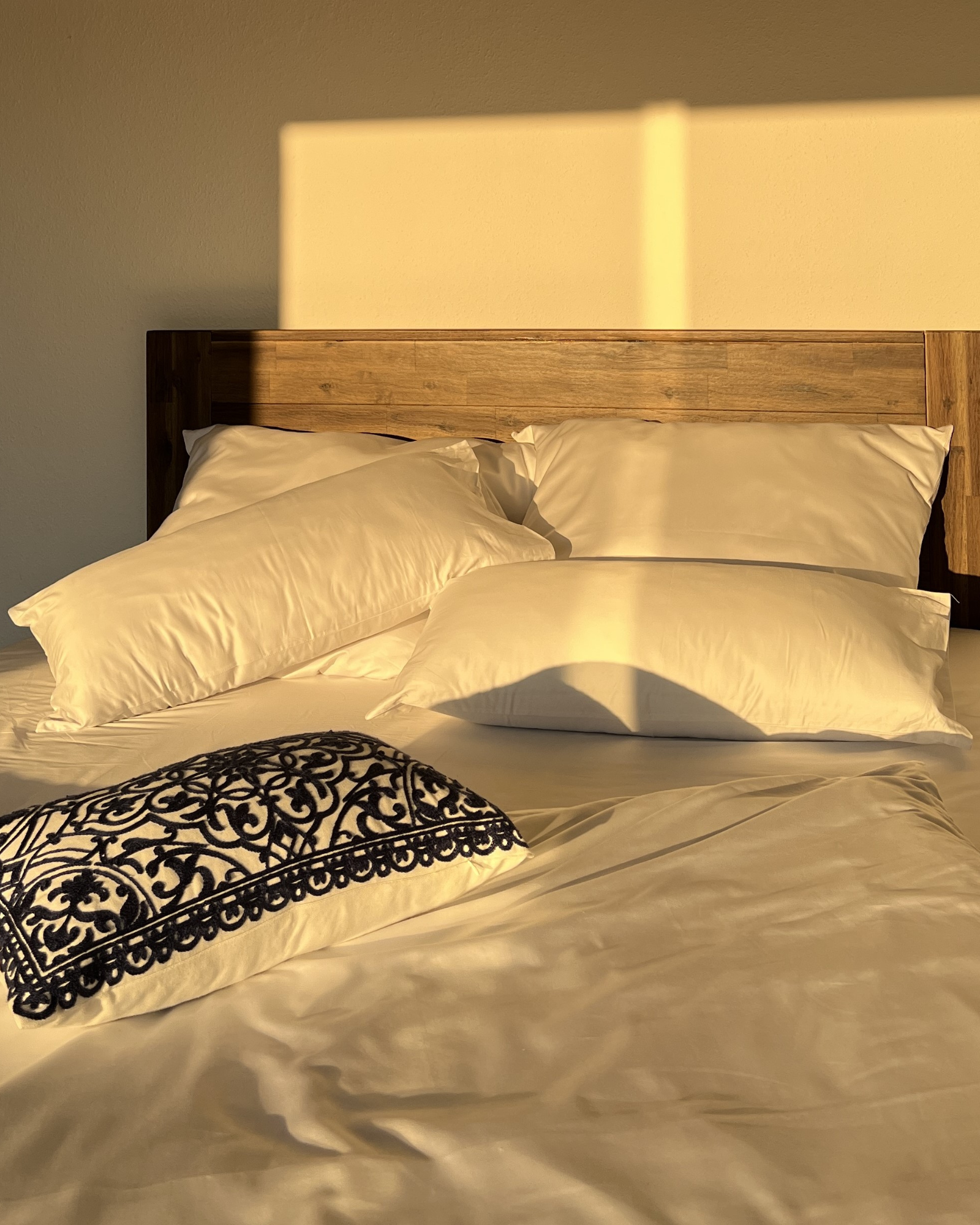 Ein weißes Bett mit Kissen, in gemütlicher Atmosphäre und Sonnenlicht.