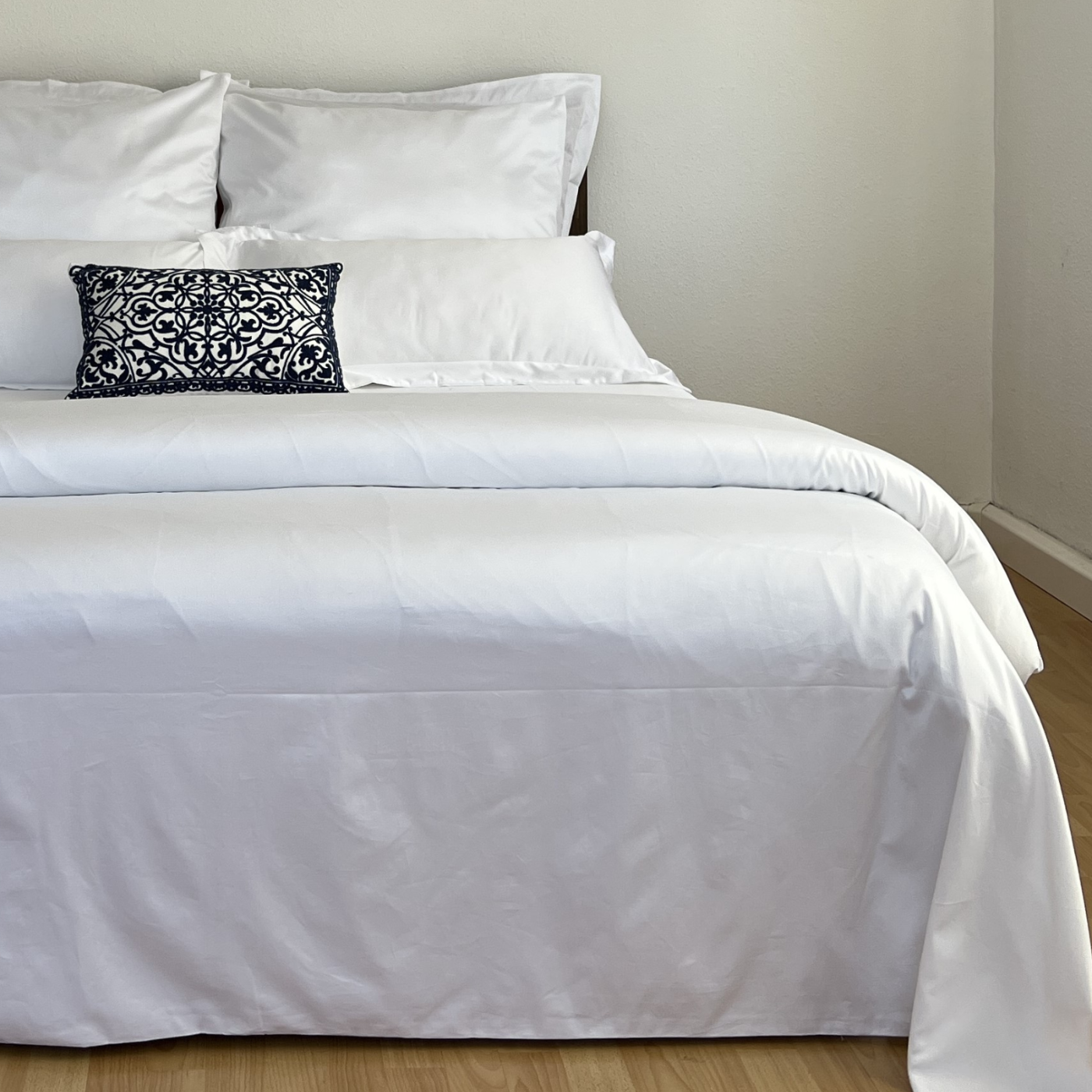 Ein Bett mit weißen Laken und Kissen, das einen Hauch von Luxus verströmt.