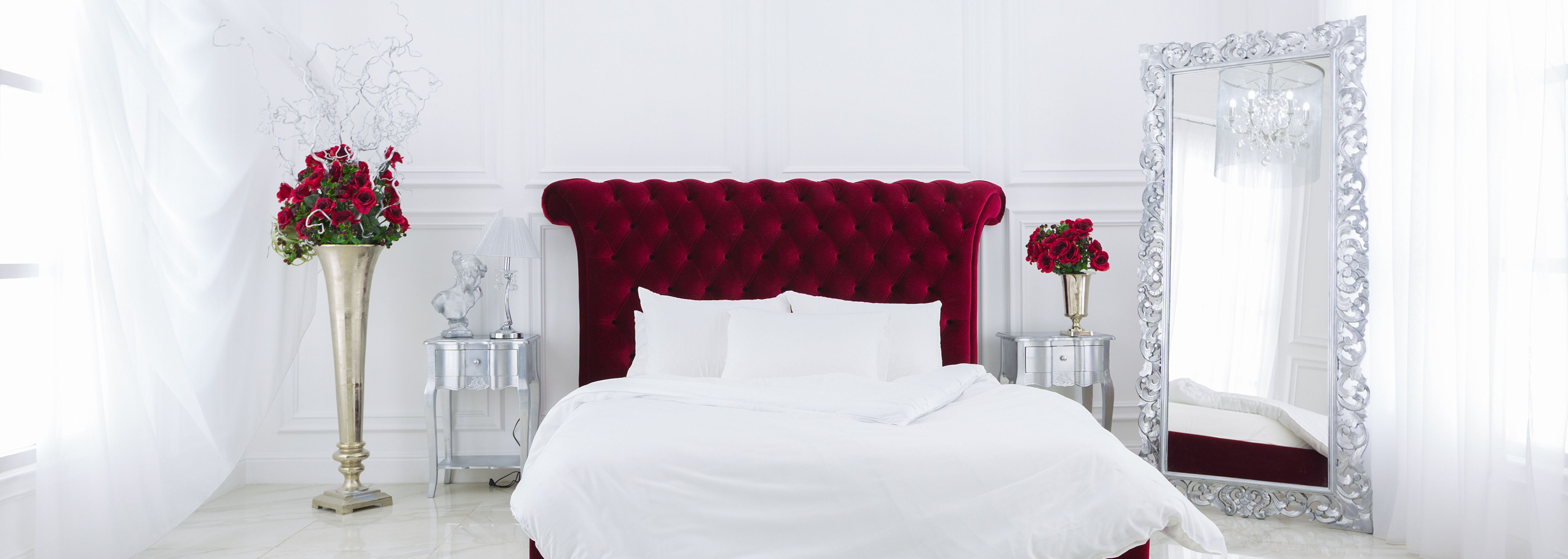 Ein weißes Bett mit rotem Kopfteil und ägyptischer Baumwollbettwäsche.